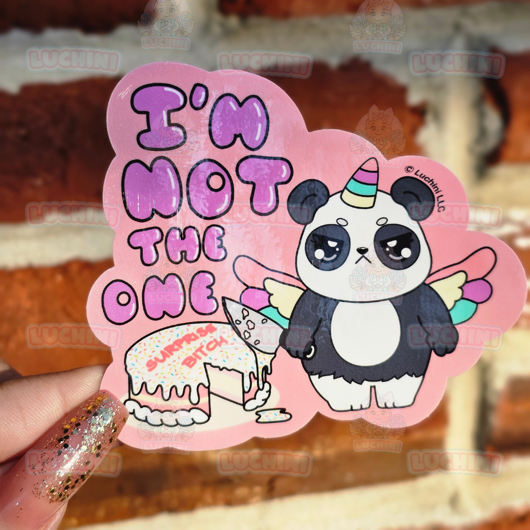 Unicorn Panda holding a knife with cake icing on it making an angry face standing next to a cake that reads " Surprise Bitch" and words to the left read " Im Not The One" 